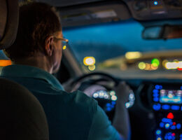 A driver looking through his windshield at blurred headlights.