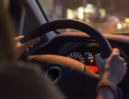 The interior of a dark vehicle with dashboard lights illuminated.