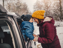 A woman and child in hats and coats in the snow.