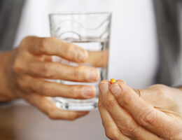  Hands hold a pill and a glass of water