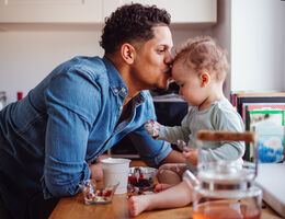  A man kisses a baby as the baby takes candy from a dish